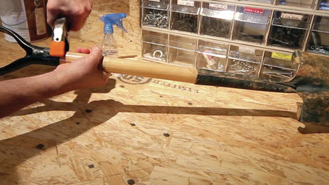 A hand gripping a wooden handle of a tool, preparing for repairs with Heavy Duty Waterproof Polyurethane Glue In Rich Brown.