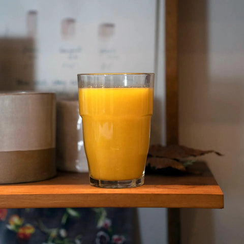 Rock Bar 16.25 Oz Cooler Glass with orange juice on shelf, part of stackable tempered glass set for cocktails at home bars