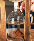 Top Shelf Portable Cold Brew Drip Tower And Iced Coffee Maker With Dual Adjustable High Borosilicate Glass Valves, close-up of glass container with coffee grounds.