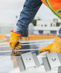 Installing 50 Pcs Aluminum Solar Panel Mid Clamps 1.06 Inch For Roof Mounts, worker securing panel with silver clamps