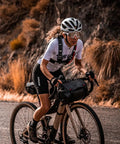 Cyclist with Waterproof Bike Handlebar Bag Rolltop 9L Front Frame Storage, bikepacking on gravel trail, secure elastic straps visible