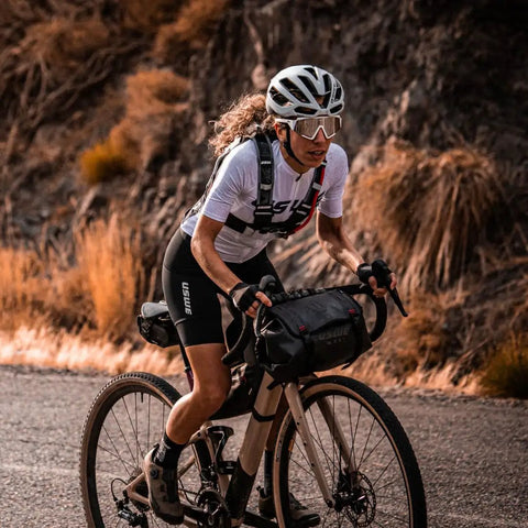 Cyclist with Waterproof Bike Handlebar Bag Rolltop 9L Front Frame Storage, bikepacking on gravel trail, secure elastic straps visible