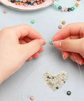 Hands threading a colorful bead with clear string, surrounded by 2 Packs Silver Soldering Sheets For Jewelry Make Secure Joints 0.08X0.08 Inch Precise Precut Soft Chips For All Metals And Creative Solder Work.