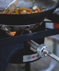 Propane Single Burner Camp Stove With High Temp Paint cooking stir-fry in wok outdoors, showing red steel braided regulator.