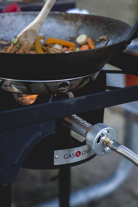 Propane Single Burner Camp Stove With High Temp Paint cooking stir-fry in wok outdoors, showing red steel braided regulator.