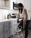Woman using Retro Style Chair And Flip Up Step Stool In White With Vinyl Seat And Steel Frame in kitchen