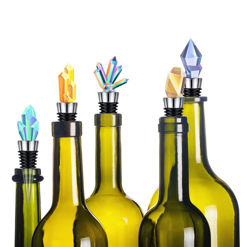 Wine bottle stoppers with metal stems and crystal gem toppers in assorted colors on green bottles (front view)