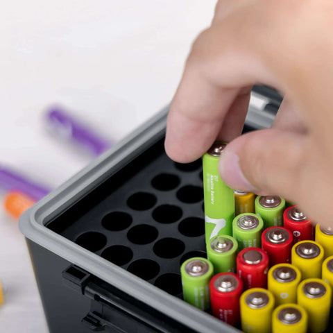 Hand placing AAA battery into the Heavy Duty Storage Box For Forty Four Aaa Batteries With Detachable Tester, showcasing organization.