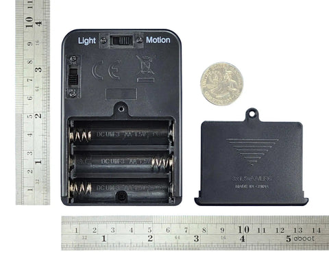 Recording Module In Black Enclosure With Dual Mode Selector Plug And Play Light Mode Or Motion Mode For Auto Display Activation By Walk By Motion Sensor Ideal For Retail Displays And Light Triggered Projects. black battery compartment back view with ruler and coin