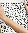 Hands applying Black and White Confetti Peel and Stick Wallpaper Removable Self-Adhesive Roll for Easy No Mess Decor, 20.5 in x 16.5 ft