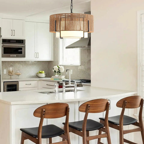 A Straight Up Game Changer 4Light Rattan Chandelier With Linen Drum Shades over a modern kitchen island with chairs.