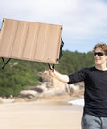 Man holding Ultralight Foldable Camping Table With Quick Setup, Sturdy And Stable Build Weighing Only 2.4 Lbs at the beach