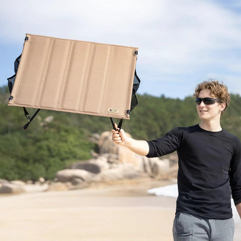 Man holding Ultralight Foldable Camping Table With Quick Setup, Sturdy And Stable Build Weighing Only 2.4 Lbs at the beach