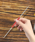Hella Tough Dual End Metal Scribe Set With Straight Hook And Angled Picks showing a hand holding a red steel scribing tool.