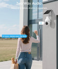Woman interacting with solar powered 2K outdoor security camera with 360 degree pan tilt, two way audio on a building wall.