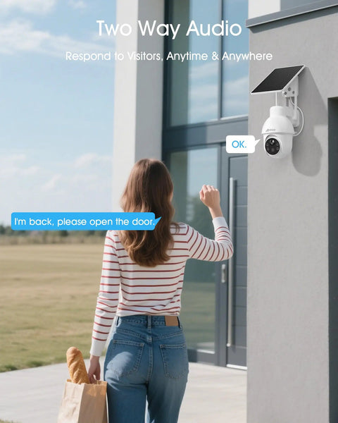 Woman interacting with solar powered 2K outdoor security camera with 360 degree pan tilt, two way audio on a building wall.