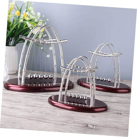 Large Newton Cradle Pendulum Desktop Physics Toy For Home Office Use Five Ball Demonstration on wooden table with plants
