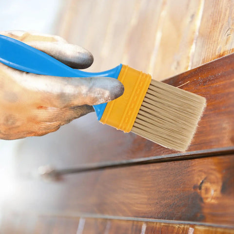 Hand using 2 Inch Nylon Bristle Paint Brush with Plastic Handle on wooden surface for DIY home projects, indoor and outdoor use.