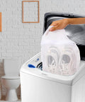 Hand placing sneakers in washing machine using Durable Sneaker Laundry Bag With Zipper And Straps, Honeycomb Mesh Wash And Dry Net