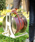 Person carrying Built Tough Stainless Steel Garden Hose Reel Featuring A Slick Auto Retracting System for outdoor use.