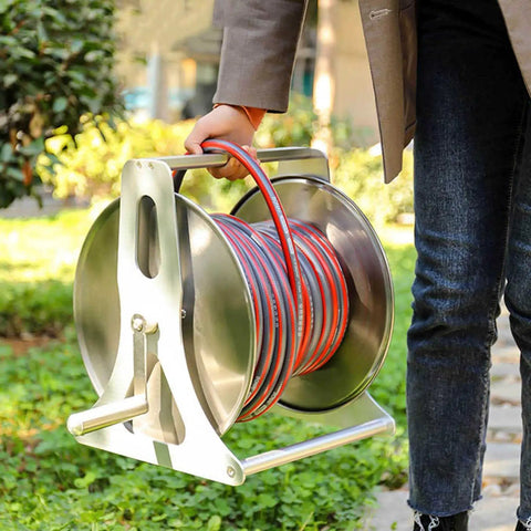 Person carrying Built Tough Stainless Steel Garden Hose Reel Featuring A Slick Auto Retracting System for outdoor use.