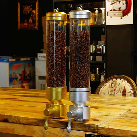 Wall Mounted Coffee Bean Dispenser With Hella Spacious Large Capacity Transparent Acrylic Jar In Slick Gold Finish and silver, showing coffee beans.