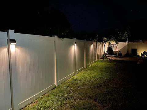 Lit Solar Fence Lights LED Outdoor Wall Lights IP65 Waterproof Eight Pack With Dual Color Modes illuminating a garden fence.