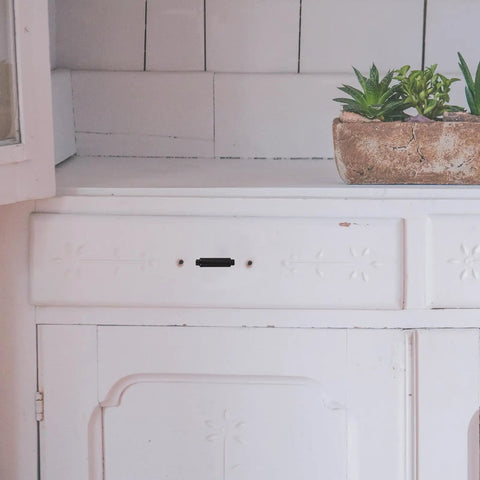 White cabinet with a missing handle next to a pot of succulents on a tiled countertop, suitable for 2 Pack Zinc Alloy Cabinet Handles For Drawers And Wardrobes, Metal Dresser Pulls, Wardrobe Door Handles, Furniture Drawer Pulls, Built To Last And Slick Cabinet Hardware For Any Home Makeover.