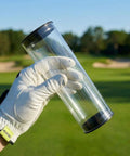 Gloved hand holding clear golf ball display tube with caps, see through PVC ball holder in outdoor setting