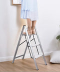 Person standing on a Three Step Aluminum Folding Ladder For Indoor And Outdoor Tasks Space Saving Slim Fold To Four Centimeter Flat.