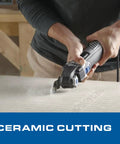 Close-up of the Badass 20V Cordless Oscillating Multi-Tool Kit with 2.0Ah Battery cutting ceramic, dust flying.