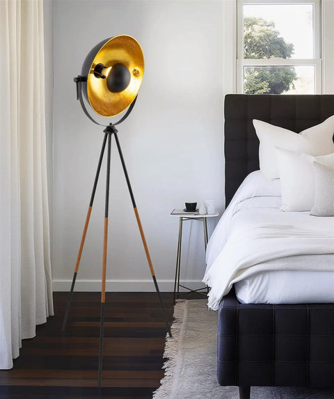 Lit Modern Tripod Floor Lamp In Black Finish With Gold Foil Circular Shade And Leather Accented Legs in bedroom corner