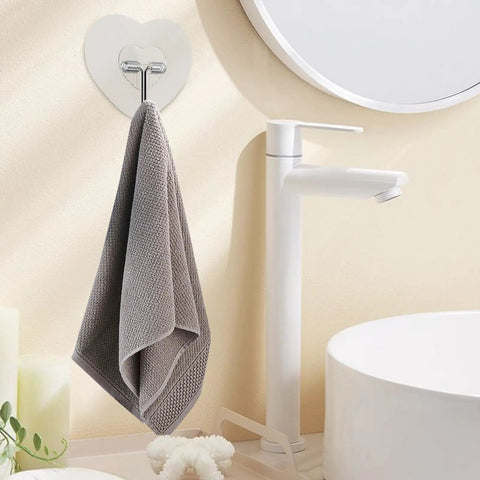 Heavy Duty Adhesive Wall Hooks With Slick Grip Keep Your Towels And Gear Locked In Place Zero Drilling Hassle Clear Transparent Look Fits Any Room Flawlessly, holding a gray towel in a bathroom setting.