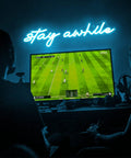 Blue "Stay Awhile" neon sign on wall above TV setup, USB powered LED bar light for bedroom, home office, party 19.7x5 inches