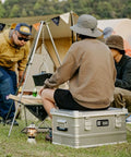Rugged Folding Storage Box With Lid Heavy Duty Aluminum Frame Stackable Gear Crate Built Tough For Camping And Picnics No Sweat Organization Haul Your Stash On The Go Rust Resistant Silver Design used as a seat and storage at a campground.