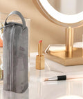 Gray travel toiletry bag with ventilated mesh storage on vanity table near makeup, road trip ready kit.