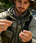 Angler using Magnetic Fly Threader For Fly Fishing Leader Stringing And Knotting Tools by a river, threading hook with ease.