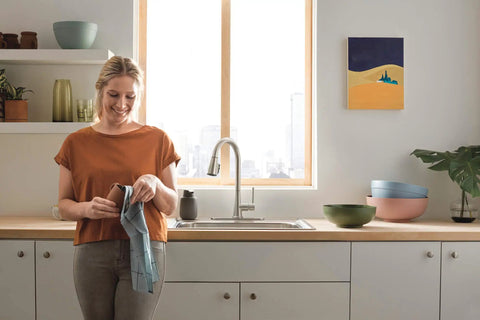 Precept Pull-Down Kitchen Faucet, 1.5 GPM Flow, Stainless Finish in modern kitchen with woman drying dish