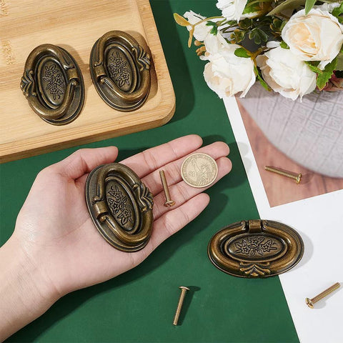 Four Pack Antique Oval Drawer Pulls in Antique Bronze, Vintage Floral Engraved Handles for Furniture, displayed with hand for scale