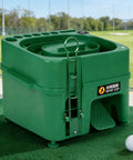 Automatic Golf Ball Dispenser And Tee Up Trainer For Driving Range And Home Practice With 40 Ball Capacity Dual Mode Height Adjustment Infrared Auto Tee System For Continuous Swing Practice Like A Pro, green unit on grass.