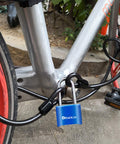 Built Tough 4 Digit Combination Padlock With 2.5 Inch Shackle, Outdoor Waterproof Lock For School Gym Locker, Storage Unit, Fence, Gate And Toolbox Blue, Resettable And Dustproof With Clear Large Digits For Easy Locking securing a bicycle on a street.