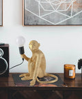 Resin Sitting Monkey Table Lamp With LED Light on a desk, stylish gold finish, ideal for living room or bedroom decor.