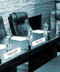 Pack Of 18 Clear Acrylic Desk Name Plates 2 By 8 Inches Blank Customizable Horizontal Slant For Office Conference Business Event Or School Classroom Great For Offices And Classrooms placed on a conference table with microphones