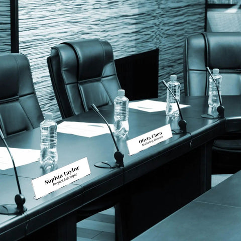Pack Of 18 Clear Acrylic Desk Name Plates 2 By 8 Inches Blank Customizable Horizontal Slant For Office Conference Business Event Or School Classroom Great For Offices And Classrooms placed on a conference table with microphones