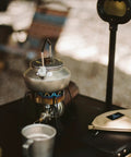 Lightweight 0.6 Liter Stainless Steel Camping Kettle with Locking Anti Hot Handle on camp stove, retro silver finish.