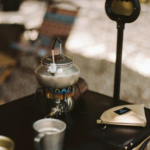 Lightweight 0.6 Liter Stainless Steel Camping Kettle with Locking Anti Hot Handle on camp stove, retro silver finish.
