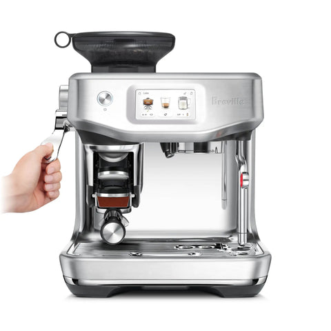 Certified Remanufactured Automatic Espresso Machine With Built In Grinder And Steam Wand showing user hand gripping portafilter.
