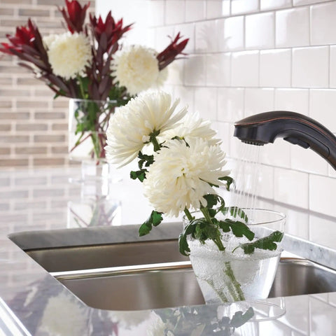Brecklyn Mediterranean Bronze Single Handle Pull Out Sprayer Kitchen Faucet With Power Clean Tech in use on flowers
