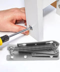 Heavy Duty 90 Degree Folding Scissor Spring Hinge for Cabinet Doors and Sofas in steel construction being installed with a screwdriver.
