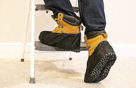 Person wearing Black Industrial Disposable Shoe Covers Extra Thick 45 GSM climbing a ladder, elastic banded cuff visible.